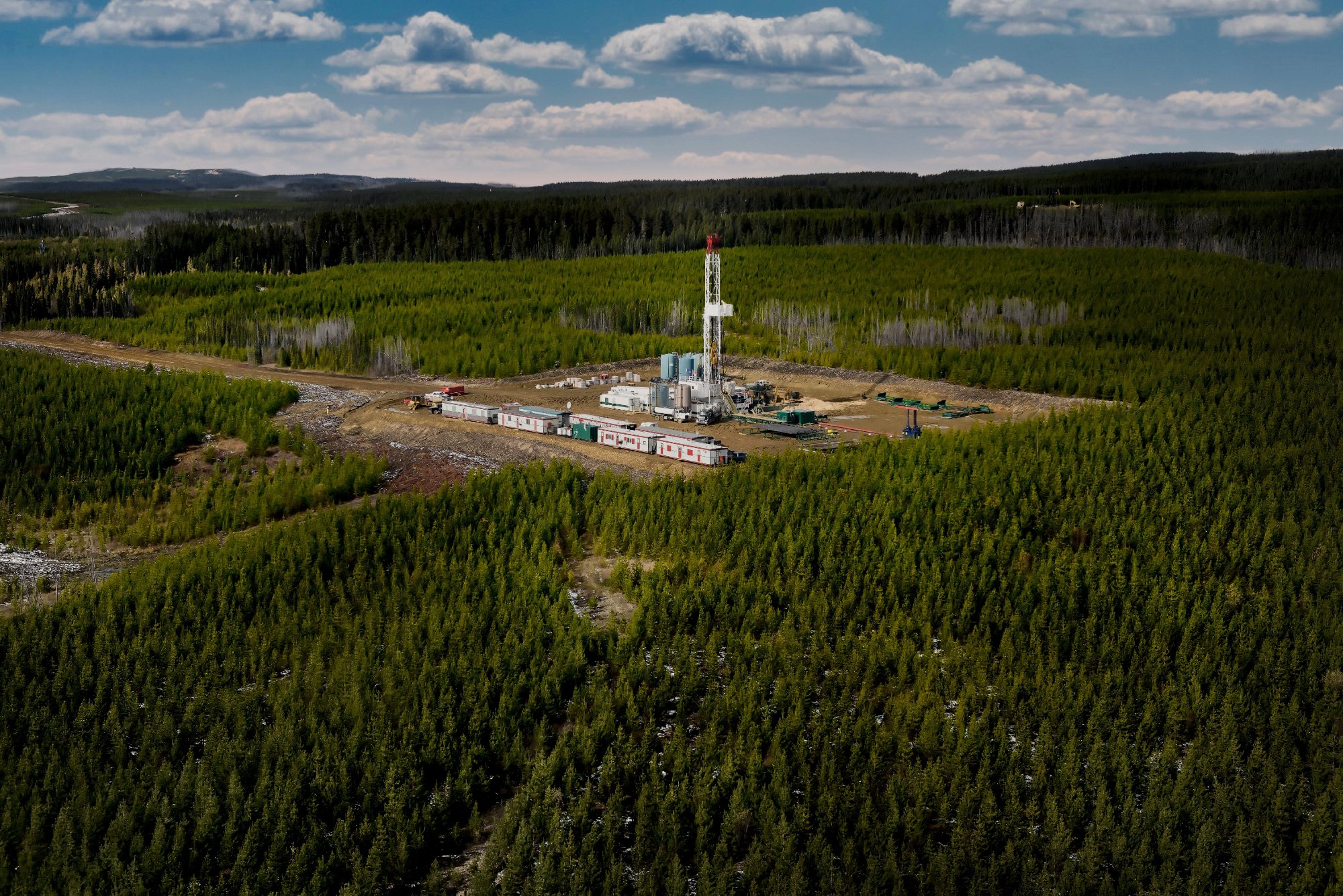 Aerial view of a drilling rig surrounded by forest